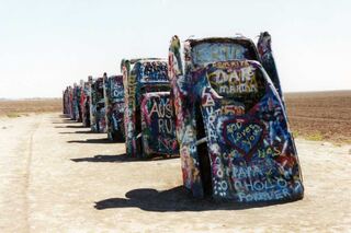 A row of hand-painted art cars parked beside a road