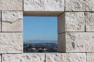 A square opening in a stone wall framing a distant view