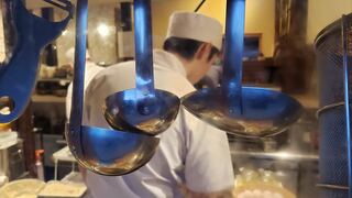 A working kitchen with hanging utensils and a cook in a white hat