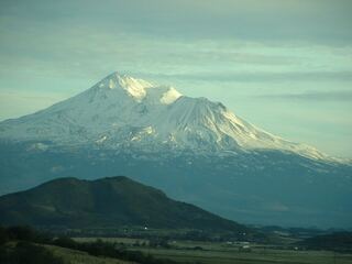 Mount Shasta rising behind green hills