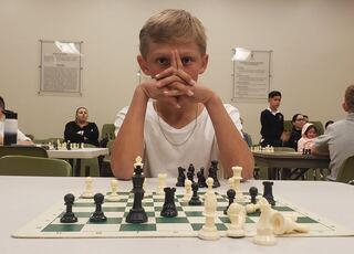 A young chess player deep in thought at a tournament table